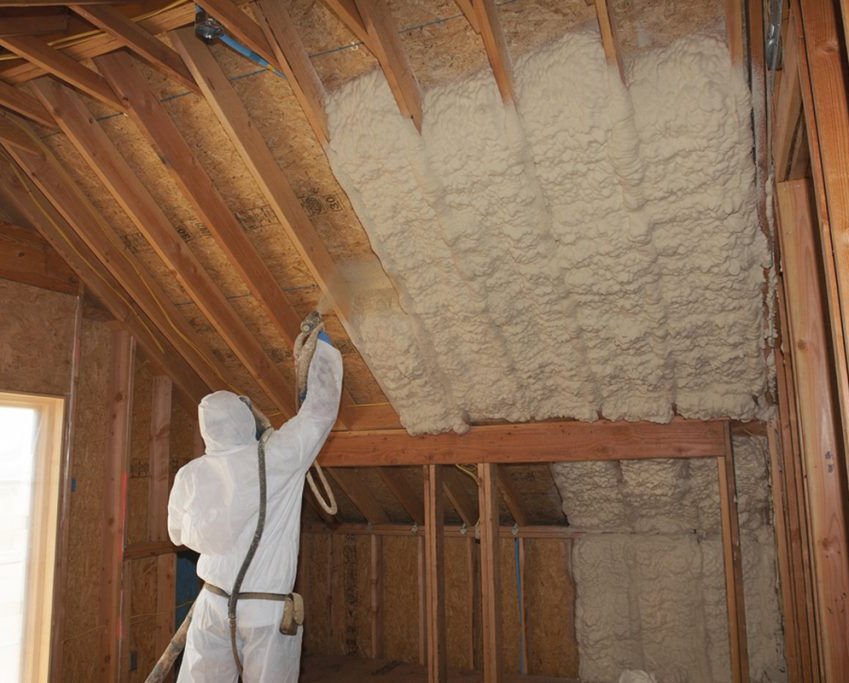 Liquid Green technician applying spray foam insulation in attic