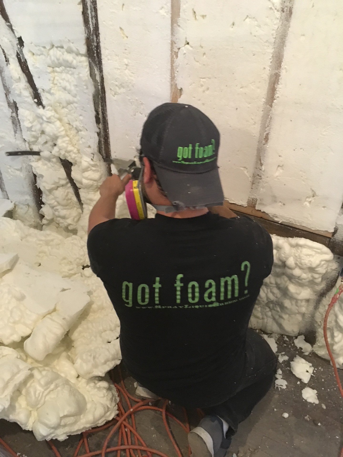Liquid Green technician on ladder spraying open cell spray foam in attic
